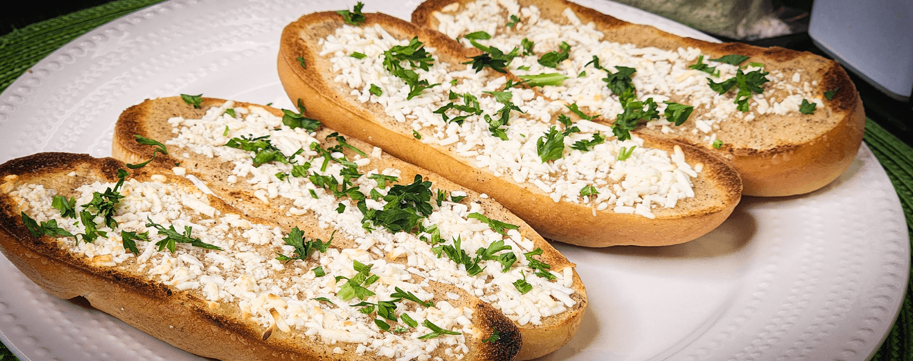 Garlic bread slices with cheese and parsley on top.