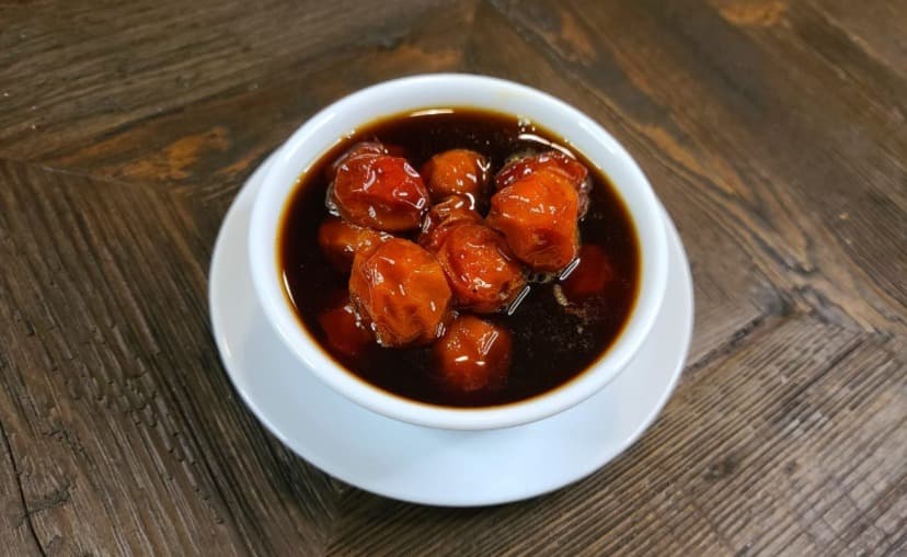 Dish with melted jocotes bathed in a honey-based sauce, decorated with cinnamon. 